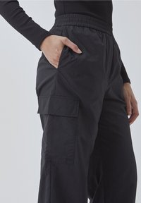 Sorte cargo bukser med elastisk talje, featuring sidelommer og et tekstureret, letvægtsstof. Enkel design og afslappet pasform.