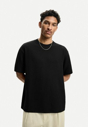 Sort kortærmet t-shirt i struktureret stof, afslappet pasform, rund halsudskæring og et glat, minimalistisk design.