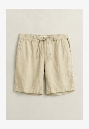 Beige legere Shorts in knielanger Länge mit elastischem Bund, Kordelzug, Knopfverschluss und Seitentaschen, flach auf hellem Hintergrund ausgelegt.
