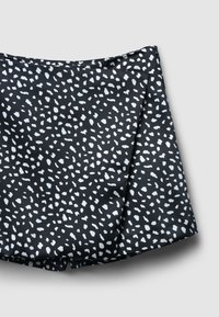 Tessuto nero con un motivo astratto bianco, caratterizzato da una texture morbida e una forma a linea A. Il design presenta una finitura liscia e una leggera caduta.