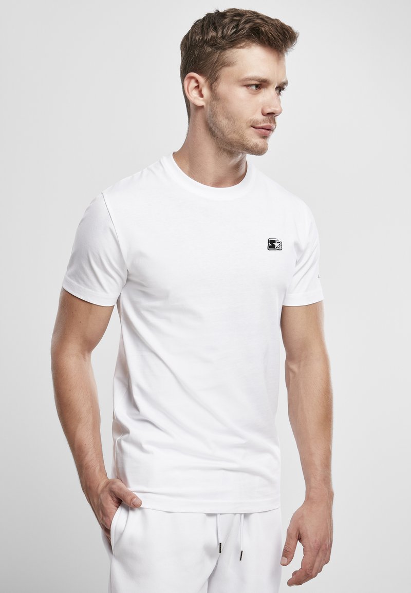 White cotton t-shirt with crew neck, short sleeves, and a small black logo on the left chest. Smooth texture, fitted design.
