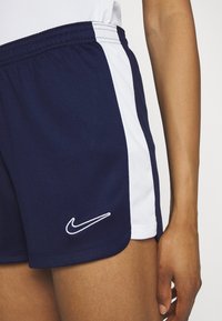 Námornícke športové šortky s bielym bočným panelom, elastickým pásom a bielym logom Nike na ľavom leme, vyrobené z ľahkej látky.