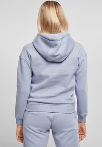 Sudadera azul claro con una gran capucha, puños y cintura acanalados. Textura suave, diseño simple, vista desde atrás con un acabado suave.