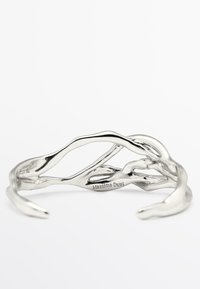 Bracciale aperto in argento con design organico e ondulato, con "Massimo Dutti" inciso all'interno, posizionato su uno sfondo bianco.