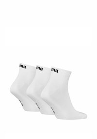 Tres pares de calcetines de algodón blanco hasta el tobillo con puños acanalados y branding negro en la parte superior, con una textura suave y un diseño sin costuras.