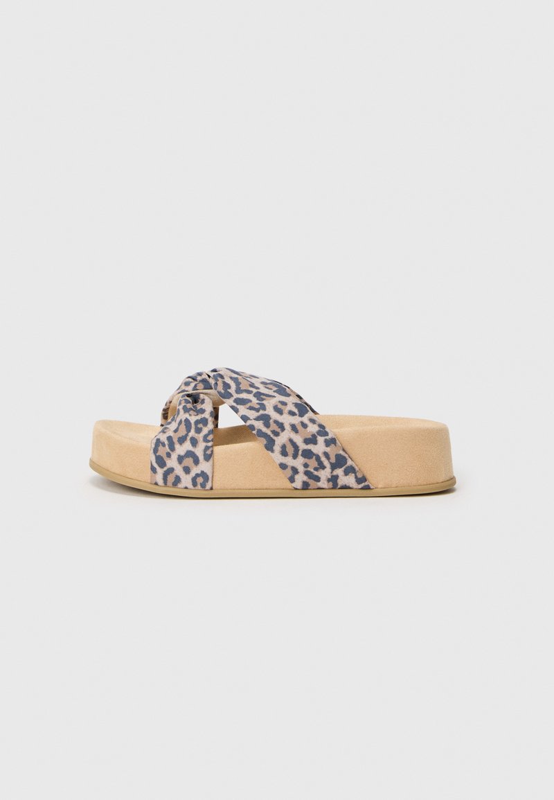 Tongs à plateforme avec une semelle en suède beige. Dotées de brides à imprimé léopard bleu qui se croisent sur le pied, offrant un design décontracté.
