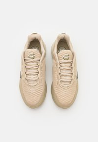 Pair of beige mesh sneakers with laces and "air max" logo on tongue, viewed from above on white background.