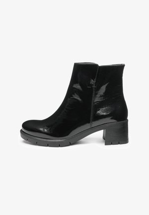 Glanzende zwarte laarzenschoen van lakleer met blokhak en profielzool, zijrits en ronde neus, zijaanzicht op witte achtergrond.