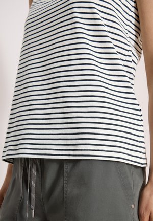 Hvid og sort vandret striped skjorte kombineret med grå bukser med snor og frontlomme med nitte detaljer.