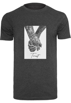 Tumedast hallist puuvillast T-särgist, mille keskosas on tätoveeritud käte graafika, mis hoiavad üksteist, allpool on kätkästi kiri "Usalda".