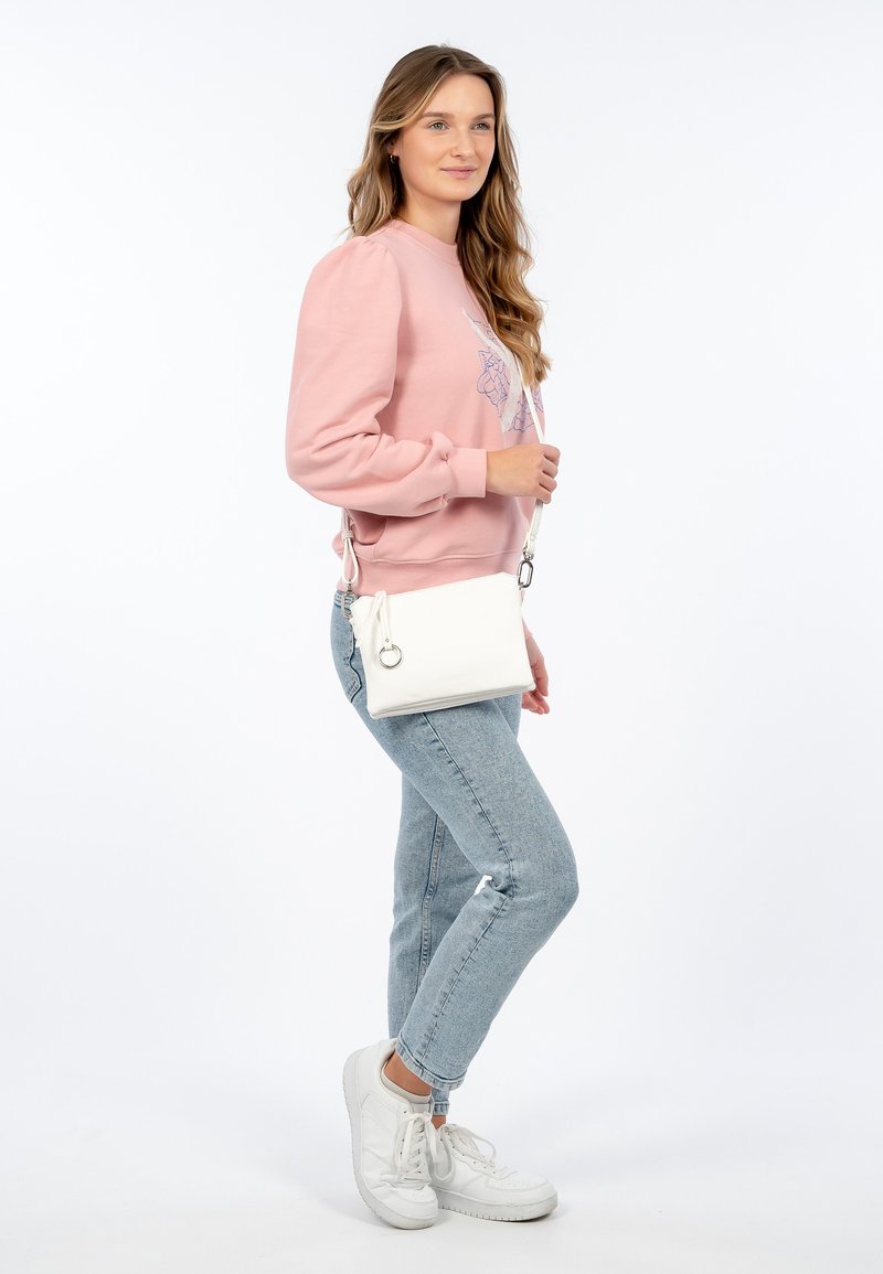 Sudadera rosa con mangas abullonadas, diseño gráfico; jeans de mezclilla clara; bolso bandolera blanco con cremallera y detalle de anillo; zapatillas blancas.