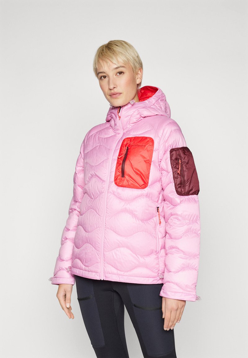 Roze pufferjack met een capuchon, voorzien van rode en bordeauxrode zakken, een geborduurd patroon en contrasterende ritsdetails.