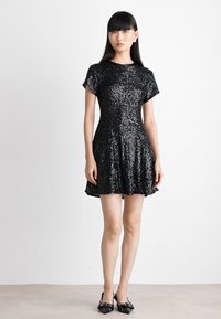 Rochie neagră din paiete cu mâneci scurte, fustă evazată și decolteu rotund. Are o suprafață texturată și un corset ajustat.