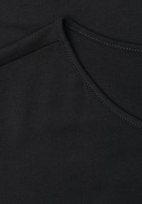 Gros plan sur un tissu en coton noir montrant des coutures croisées et des détails de couture.
