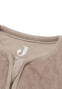 Vêtement zippé beige clair avec un mélange de textures en coton et en polaire. Il dispose d'un col rond et d'un petit logo sur l'étiquette intérieure.
