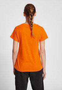 Kortärmad orange t-shirt med rund halsringning, mjuk textur och en något böjd fåll, sedd bakifrån.