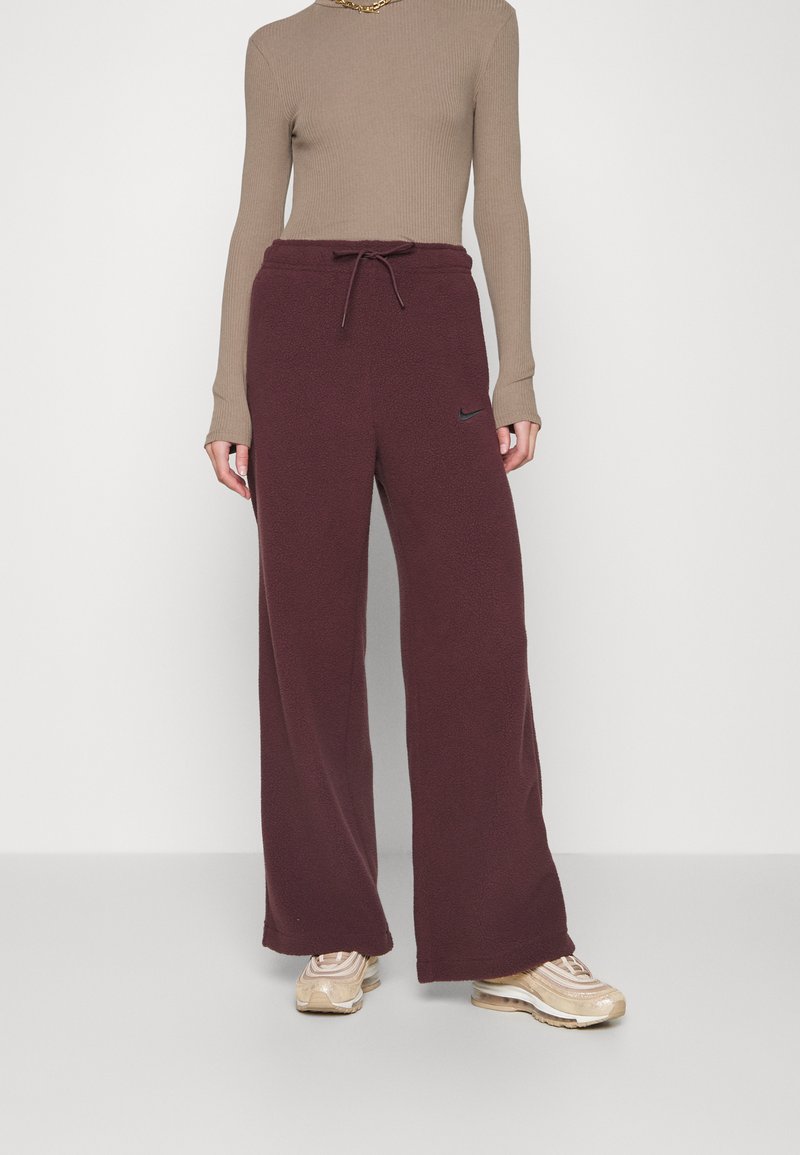 Pantalons de survêtement en polaire bordeaux avec une taille à cordon, jambes larges, et un petit logo Nike noir sur la zone de la poche gauche.
