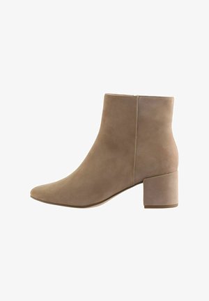 Botte de cheville beige en daim, dotée d'un bout pointu et d'un talon chunky et rectangulaire pour la stabilité. Texture lisse avec un design minimaliste.