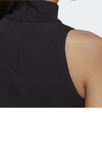 Černý top bez rukávů s vysokým límcem, s hladkým povrchem a detailem zadního zipu, který zdůrazňuje přiléhavý střih.