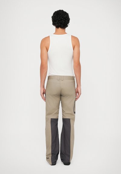 Beige broek met donkergrijze panelen, gemaakt van stevig materiaal. Heeft een recht model, riemlussen en zijzakken.
