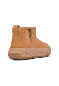 Bottines en suede tan avec une fermeture éclair sur le côté, semelle en caoutchouc texturée et design à plateforme surélevée. Présente un détail de logo sur le côté.