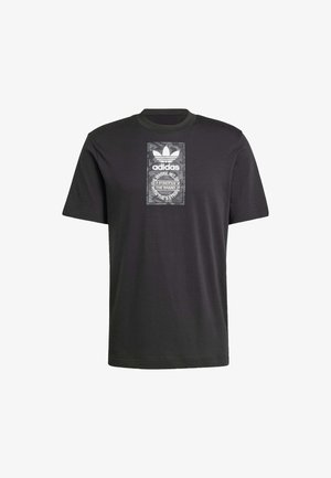 Camiseta de algodón negra con cuello redondo, que presenta un estampado gráfico rectangular con el logo de Adidas y un texto circular superpuesto.