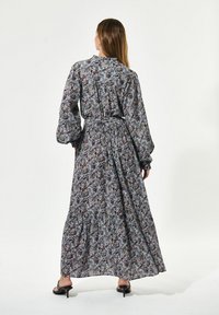 Florale maxi-jurk met een hoge kraag, lange pofmouwen, een getailleerde taille en een gerimpelde zoom; heeft een blauw, paars en groen patroon.