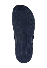 Black rubber shoe sole featuring a textured pattern, ridges for grip, and a smooth rounded heel with a branded logo.