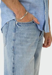 Ljusblå denimjeans med en avslappnad passform, med en framficka, subtilt bleknade detaljer och en liten metallknapp i midjan.