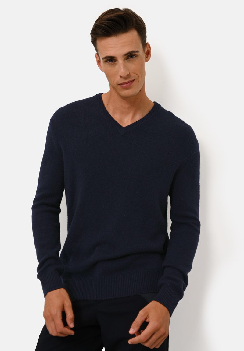 Marineblaues V-Ausschnitt-Pullover aus weichem Strickstoff, ausgestattet mit gerippten Bündchen und Saum, die eine figurbetonte, aber dennoch bequeme Silhouette bieten.