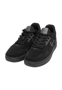 Sorte sneakers med en kombination af ruskind og syntetiske materialer, der har en polstret krave, flade snørebånd og en gummisål.
