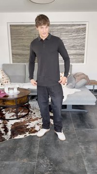 Μαύρο polo πουκάμισο με μακριά μανίκια και μαύρο cargo παντελόνι, σε συνδυασμό με λευκά αθλητικά παπούτσια. Εσωτερικός χώρος με γκρίζο καναπέ και μοτίβου χαλί.