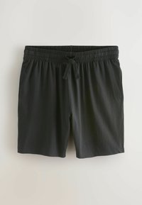 Fekete, rugalmas derékú nadrág, húzózsinórral, egyenes szabású, puha anyagból készült, sima világos háttér előtt lóg.