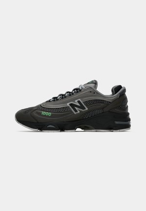 Zwarte en grijze sportieve schoen met meshpanelen, gevoerde kraag en reflecterende accenten. Voorzien van een groen "1000" logo. Rubberen zool.