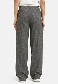 Weite Hosen im Hahnentrittmuster; aus einem strukturierten Stoff in Schwarz und Weiß; mit hohem Bund und dezentem Nähten.