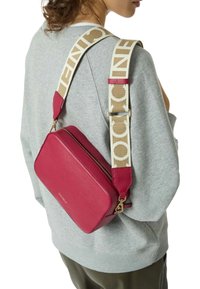 Borsa a tracolla in pelle magenta con forma rettangolare, dotata di una tracolla beige con stampa del logo e finiture in tonalità oro.