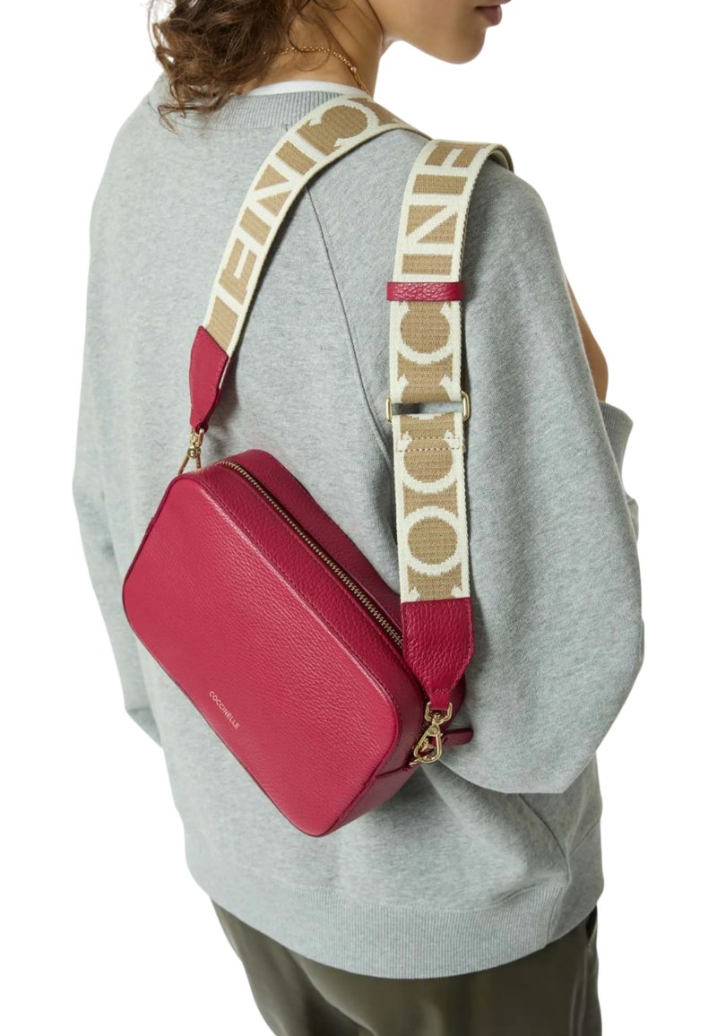 Borsa a tracolla in pelle magenta con forma rettangolare, dotata di una tracolla beige con stampa del logo e finiture in tonalità oro.