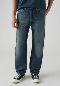 Jeans in denim blu chiaro con vestibilità rilassata e gambe dritte, caratterizzati da un classico design a cinque tasche e dettagli di cucitura a contrasto.