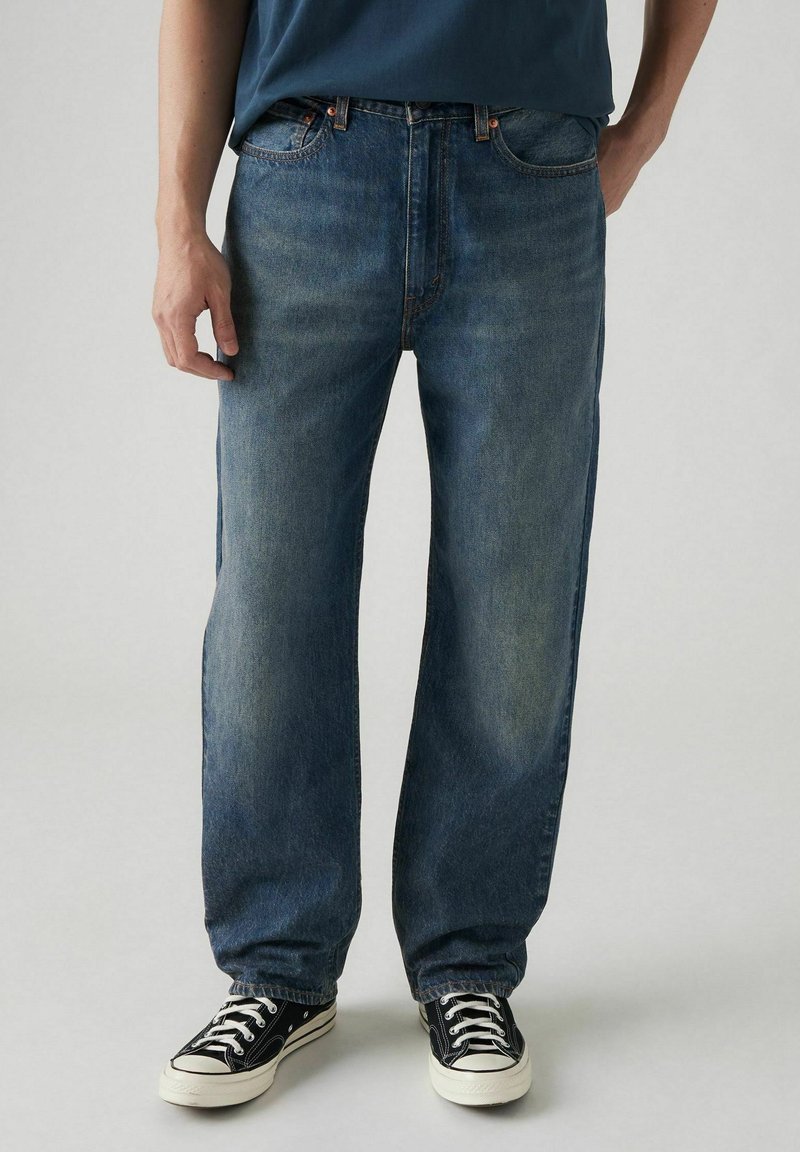 Jeans in denim blu chiaro con vestibilità rilassata e gambe dritte, caratterizzati da un classico design a cinque tasche e dettagli di cucitura a contrasto.