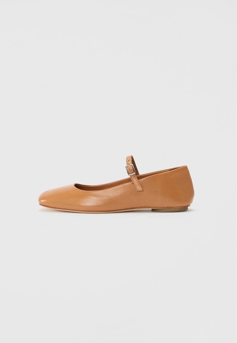 Bailarinas de pele castanha com bico redondo, tira no tornozelo e salto baixo. Textura suave e design minimalista em fundo simples.