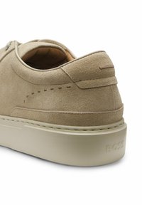 Talons de baskets en daim beige avec col rembourré et semelle épaisse en caoutchouc embossée du logo « BOSS » sur fond blanc.