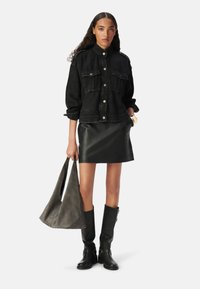 Giacca di jeans nera con tasche frontali, gonna in pelle attillata, borsa a tracolla in suede grigio e stivali neri al ginocchio. Tessuti lisci e vestibilità sartoriale.
