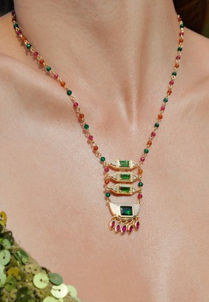Collier en or ornée de rangées de pierres précieuses vertes et roses, avec un design à motifs et des perles colorées le long de la chaîne.