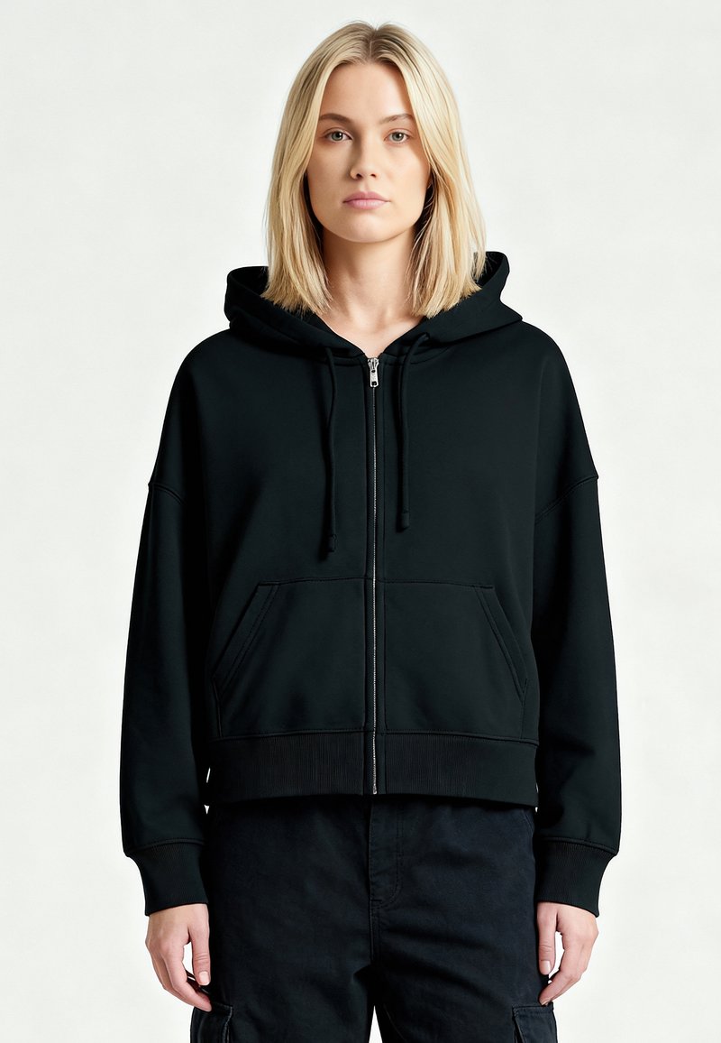 Schwarzer, kürzer geschnittener Hoodie mit Reißverschluss vorne, großer Kapuze und zwei Vorderseiten-Taschen. Weicher Stoff, Rippbündchen an Ärmeln und Saum, minimalistisches Design.