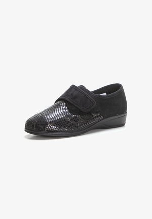 Zapatos negros con un patrón de reptil texturizado y brillante en la puntera, parte superior de suave ante negro, correa de Velcro ajustable y un tacón bajo y curvado.