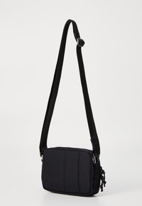 Geantă crossbody neagră din material captusit; formă dreptunghiulară cu o suprafață texturată, curea ajustabilă și închidere cu fermoar.