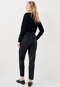 Marinblå stickad tröja i kombination med svarta skräddarsydda byxor. Byxorna har en smal passform, bälteshällor och en enkel baksida ficka.