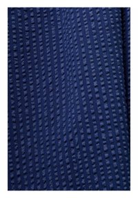 Tissu bleu marine avec un motif texturé de points verticaux en relief et de fines rayures créant une surface tactile.