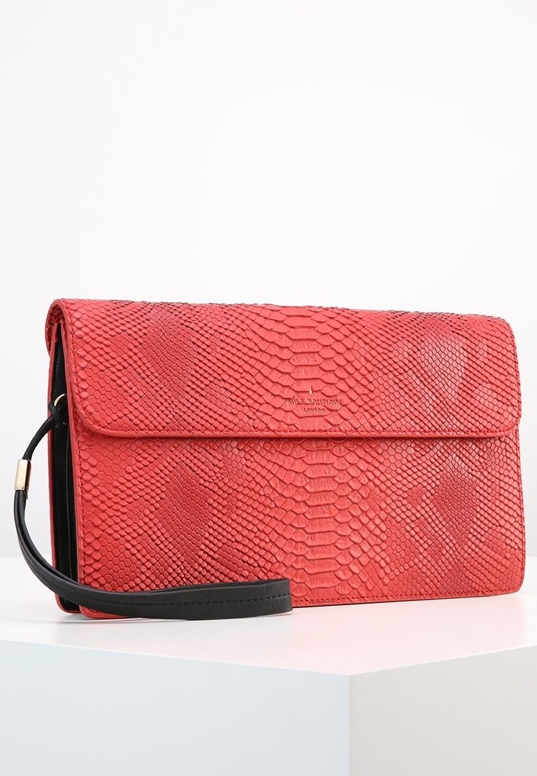 Czerwona torebka kopertówka o fakturze węża z czarnym skórzanym paskiem i klapką. Zawiera złote logo z przodu.