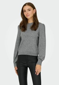 Grauer Strickpullover mit langen, puffigen Ärmeln und einem gerippten Saum. Kombiniert mit schwarzen, schmal geschnittenen Hosen. Einfaches Design, weicher Stoff.